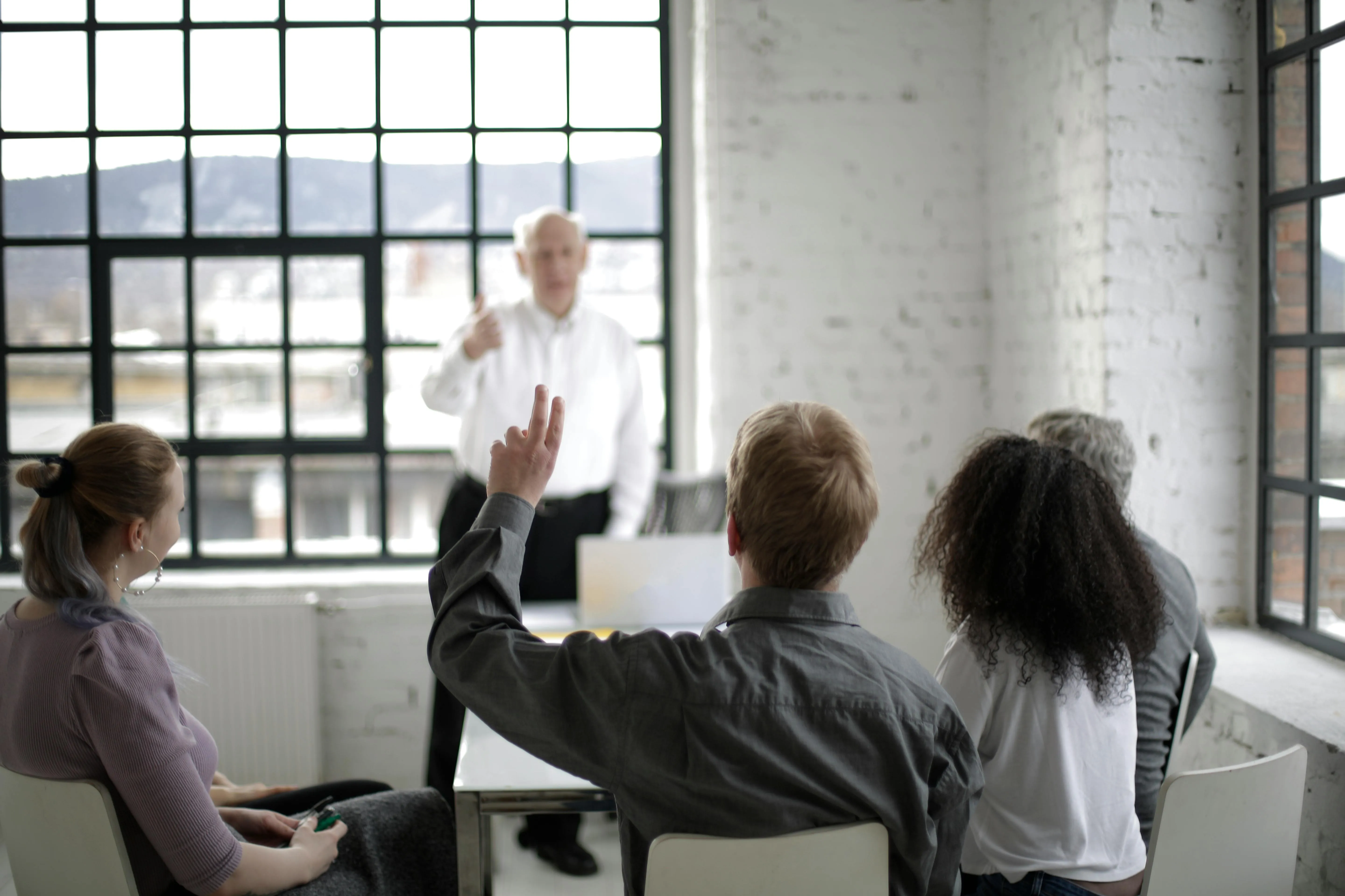 A man raises his hand to ask a question in a classroom