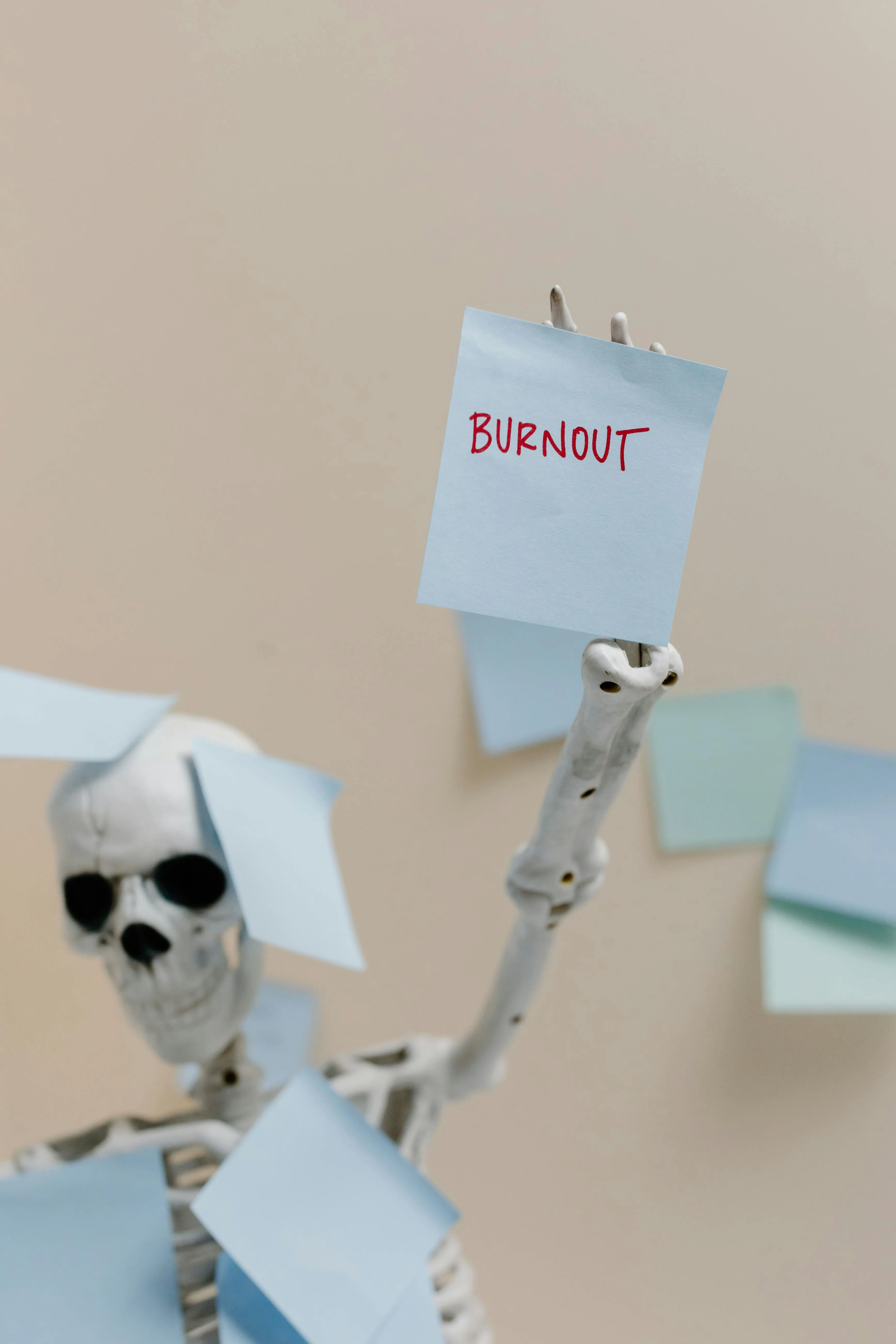 A skeleton plastered in office paper holding a note that says burnout