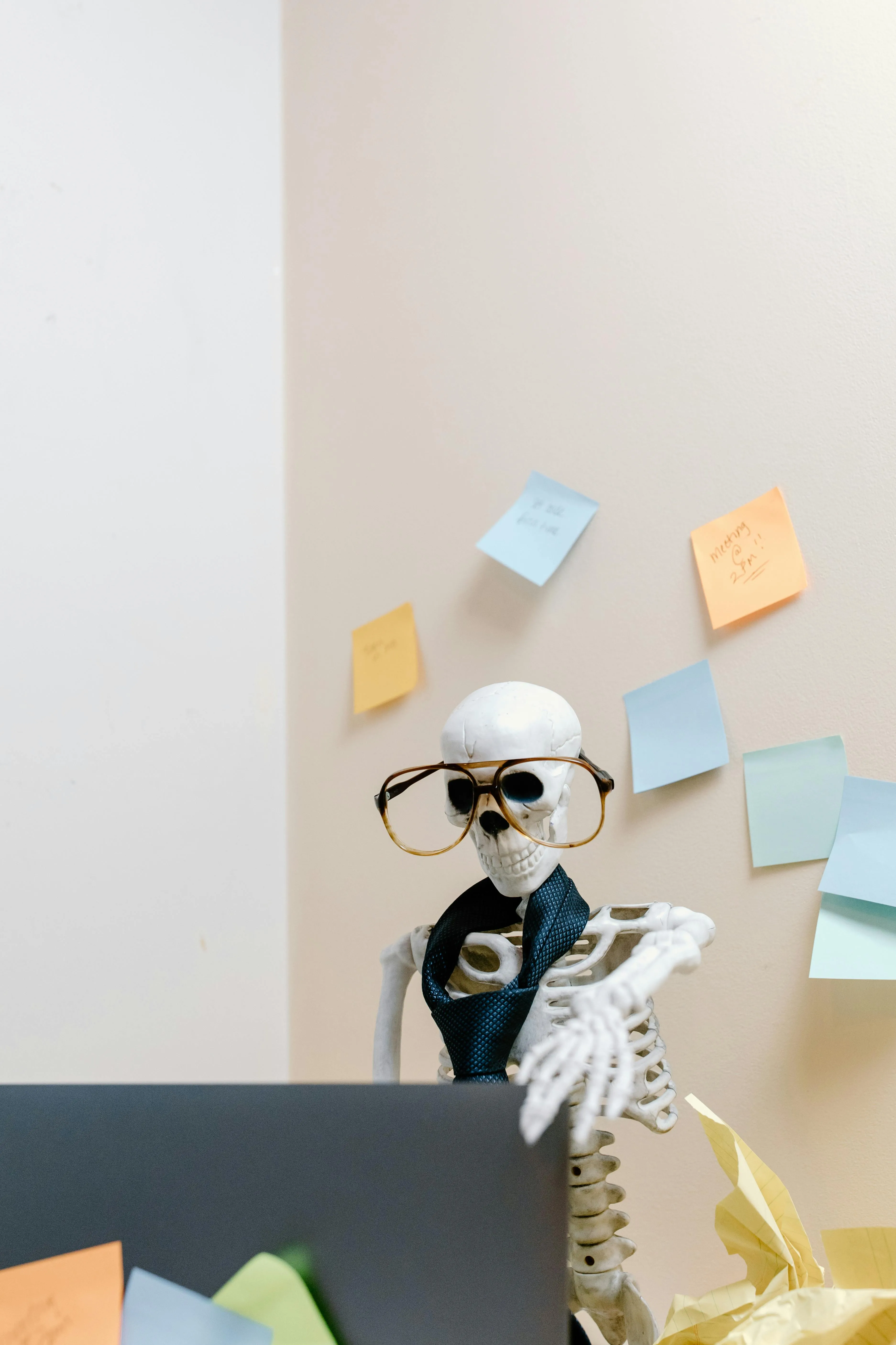 A skeleton sitting at a computer wearing a tie